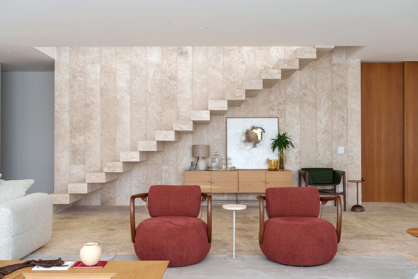 Sala de estar com poltronas e escada de mármore travertino